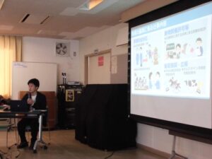 講師がプロジェクターに映し出された映像の説明をしているところ